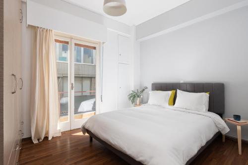 una camera bianca con un grande letto e una finestra di Super Central Apartment Downtown Exarcheia! ad Atene