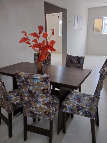 a dining room table with chairs and a vase with flowers at New House Temporada in João Pessoa
