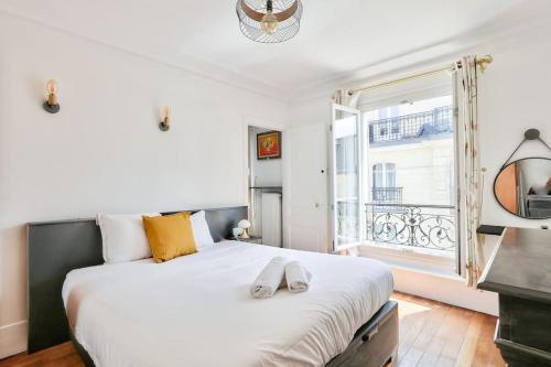 Un dormitorio con una gran cama blanca y una ventana en Superbe T2 au cœur du 17ᵉ arrondissement, en París
