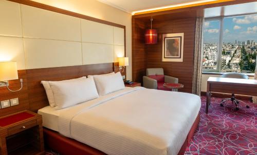 a bedroom with a bed and a desk and a window at Crowne Plaza Amman by IHG in Amman