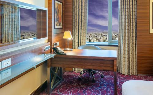 a hotel room with a desk and a window at Crowne Plaza Amman by IHG in Amman
