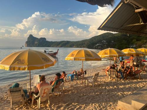 een groep mensen op een strand met parasols bij Phi Phi Ocean Club in Phi Phi Don