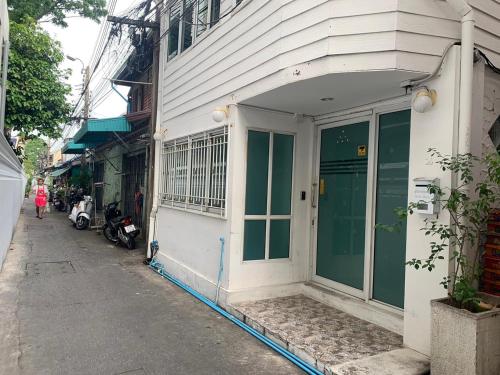 a white building with a green door on a street at Green Apple Hostel Khaosan in Bangkok