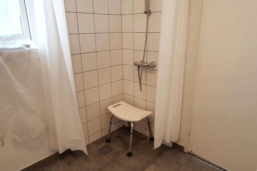 y baño con ducha y silla blanca. en Blokhus-Hune/hus 148m², 12-pers. m/privat Gårdhave, en Blokhus