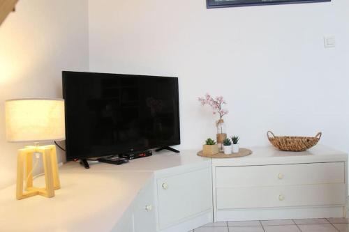 a flat screen tv sitting on top of a white dresser at Un cocon au bord de l'eau in Binic-Etables-sur-Mer