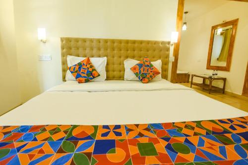a bedroom with a large bed with colorful pillows at FabHotel Grand Royal Palms in Benaulim