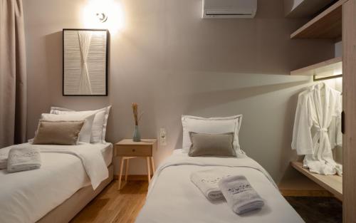 two beds in a room with white walls at Numa Suites & Lofts Athens in Athens