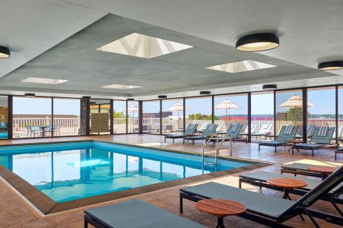 una piscina con sillas, mesas y ventanas en Delta Hotels by Marriott Muskegon Convention Center, en Muskegon