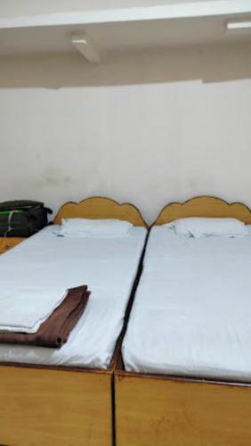 a bed with two white sheets on top of it at Rohilla's Tourist Guest House,Bhubaneswar in Bhubaneshwar