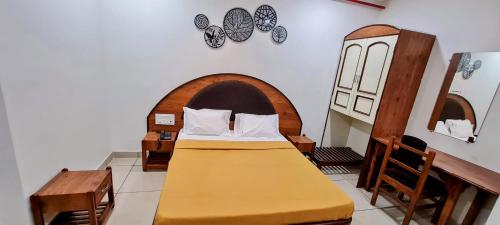 - une chambre avec un lit et une tête de lit en bois dans l'établissement HOTEL TIRTH, à Ankleshwar