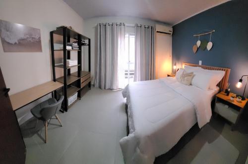 Un dormitorio con una gran cama blanca y una ventana en Sobrado em ótima localização., en Criciúma