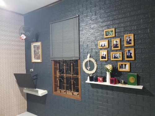 um quarto com uma parede preta com fotografias e uma janela em Loot's house em Kalianget