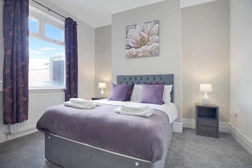 a bedroom with a bed with purple pillows and a window at Spacious Retreat with Backyard Bliss, Sleeps 7 in Bishop Auckland