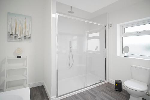 a white bathroom with a shower and a toilet at Spacious Retreat with Backyard Bliss, Sleeps 7 in Bishop Auckland