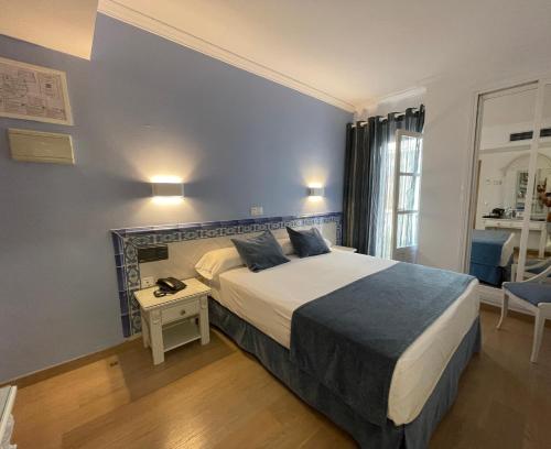 a hotel room with a bed and a table and a window at Hotel Plaza Cavana in Nerja