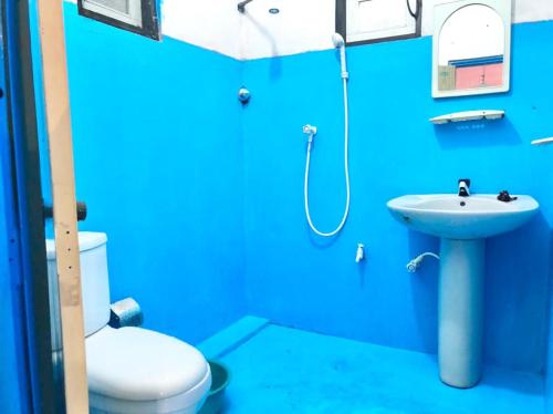 a blue bathroom with a toilet and a sink at Sunset Beach Cabana in Ambalangoda