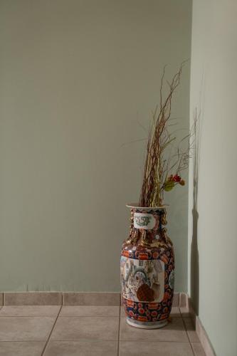 a vase with a plant in it sitting on a floor at Delphian Colors - Red Edition in Delfoi