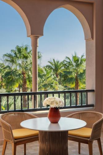 a table and chairs in a balcony with palm trees at Four Seasons Resort Marrakech in Marrakech