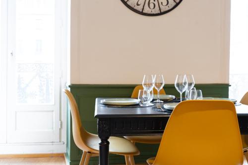 une salle à manger avec une table noire et des chaises jaunes dans l'établissement Chez Louise et Paul, l'Appart du Centre, à Dinan