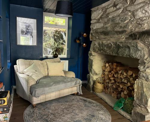 a living room with a couch and a stone fireplace at Terfyn Cottage in Dinorwic