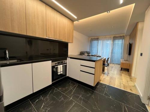 a kitchen with white cabinets and black counter tops at Refugio alpino a 5 min de pistas in Encamp