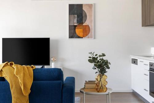 a living room with a blue couch and a tv at Caulfield Elegance: Chic Abode in Melbourne