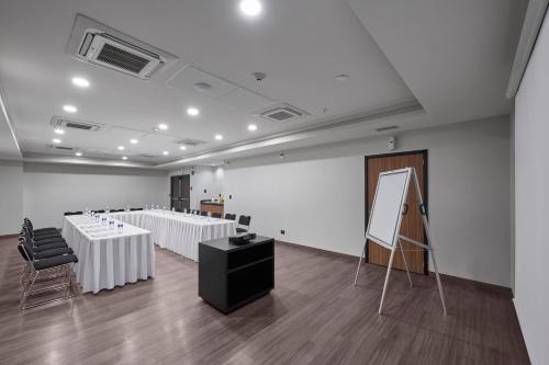 a room with white tables and chairs and a screen at City Express by Marriott Monterrey Lindavista in Monterrey