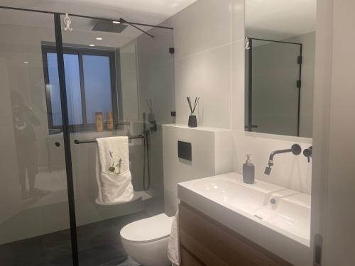 een witte badkamer met een toilet en een wastafel bij Netanya-Appartement - 5p in Netanya