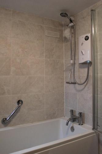 a bathroom with a bath tub and a shower at Terfyn Cottage in Dinorwic