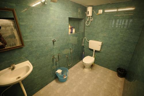 een groene badkamer met een wastafel en een toilet bij Genga Nilayam Homestay in Virudunagar