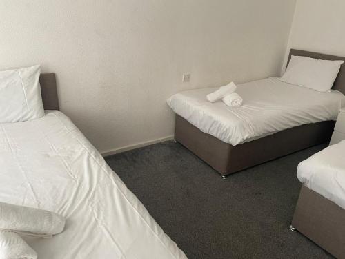 two beds in a small room with white sheets at Serene Apt in the Heart of Stretford in Manchester