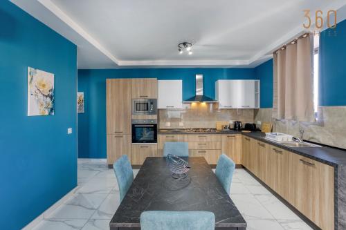 uma cozinha com paredes azuis e uma mesa e cadeiras em Relaxing 2BR home with Private Balcony in Mellieha by 360 Estates em Mellieħa