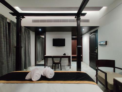 a bedroom with a bed and a table with a tv at Hotel Saratharajans in Madurai