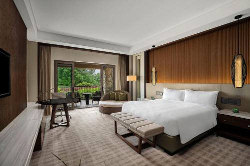 JW Marriott Hotel Zhejiang Anji في انجى: غرفة نوم بسرير كبير وبلكونة