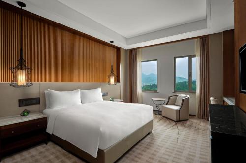 a bedroom with a large white bed and a chair at JW Marriott Hotel Zhejiang Anji in Anji
