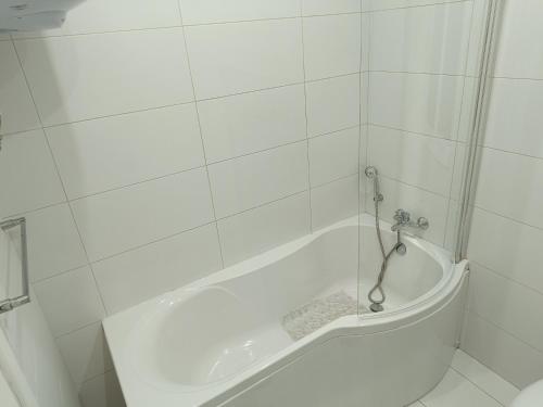 una vasca da bagno bianca in un bagno piastrellato bianco di Cosy,central,modern Gem a San Pawl il-Baħar