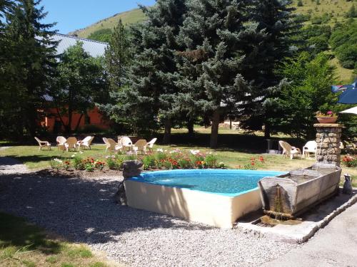 a swimming pool in a yard with chairs and trees at Le Relais du Galibier in Valloire