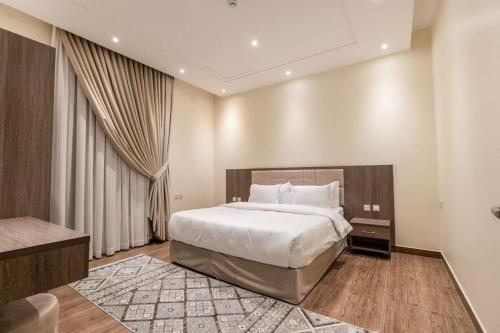 ein Schlafzimmer mit einem großen Bett und einem großen Fenster in der Unterkunft Nuzul R141 - Elegant Apartment in Riad