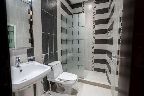 uma casa de banho com um WC branco e um lavatório. em Nuzul R141 - Elegant Apartment em Riyadh