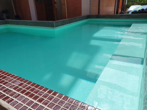 uma piscina com água azul numa casa em Pousada Bella Rosa - Capão da Canoa em Capão da Canoa
