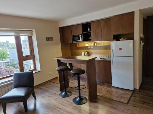cocina con nevera, mesa y sillas en Alto Rolando Apartamentos en San Carlos de Bariloche