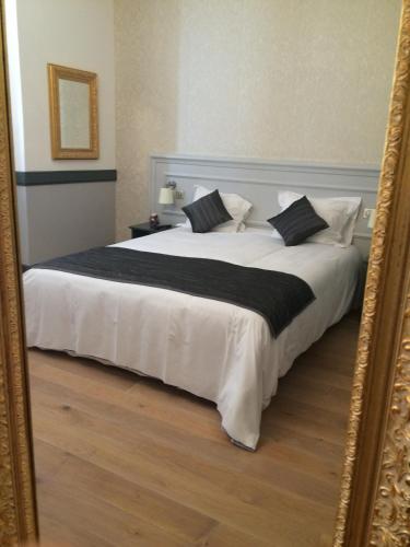 a bedroom with a large white bed with a mirror at Hotel Restaurant Edmond's in Cap d'Ail