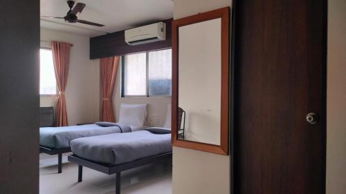 a hotel room with two beds and a mirror at Hotel Sai Nidhi Executive-MindSpace Airoli Navi Mumbai in Navi Mumbai