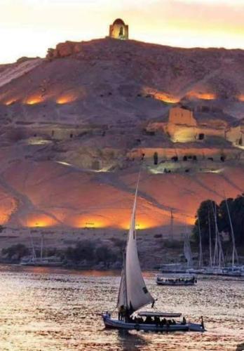 a sailboat in the water in front of an island at جوله بفلوكه في نهر النيل in Aswan