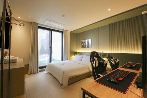 um quarto de hotel com uma cama e uma secretária com um computador em Hotel Aria em Cheonan