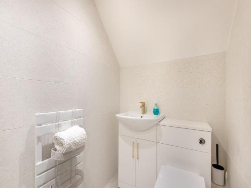 a white bathroom with a toilet and a sink at Rock Lodge in Cromford