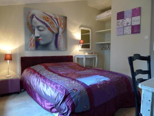 a bedroom with a bed with a painting on the wall at Gite Nuance in Saint-Aignan