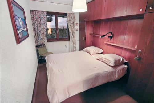 a small bedroom with a bed with a lamp on it at Charmant appartement avec vue sur les montagnes in Crans-Montana