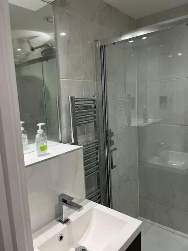 een witte badkamer met een wastafel en een douche bij 1 Bed Flat in Burton