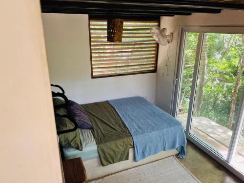 a bedroom with a bed in a room with a window at Agora at Playa Maderas - Surf House, Cabanas and Casitas in Playa Maderas